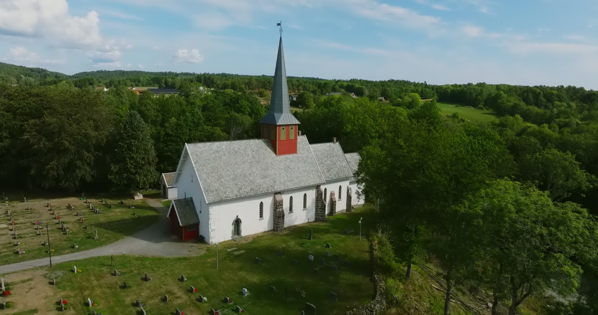 Church on wooded ridge above farmland, Rykene, Norway