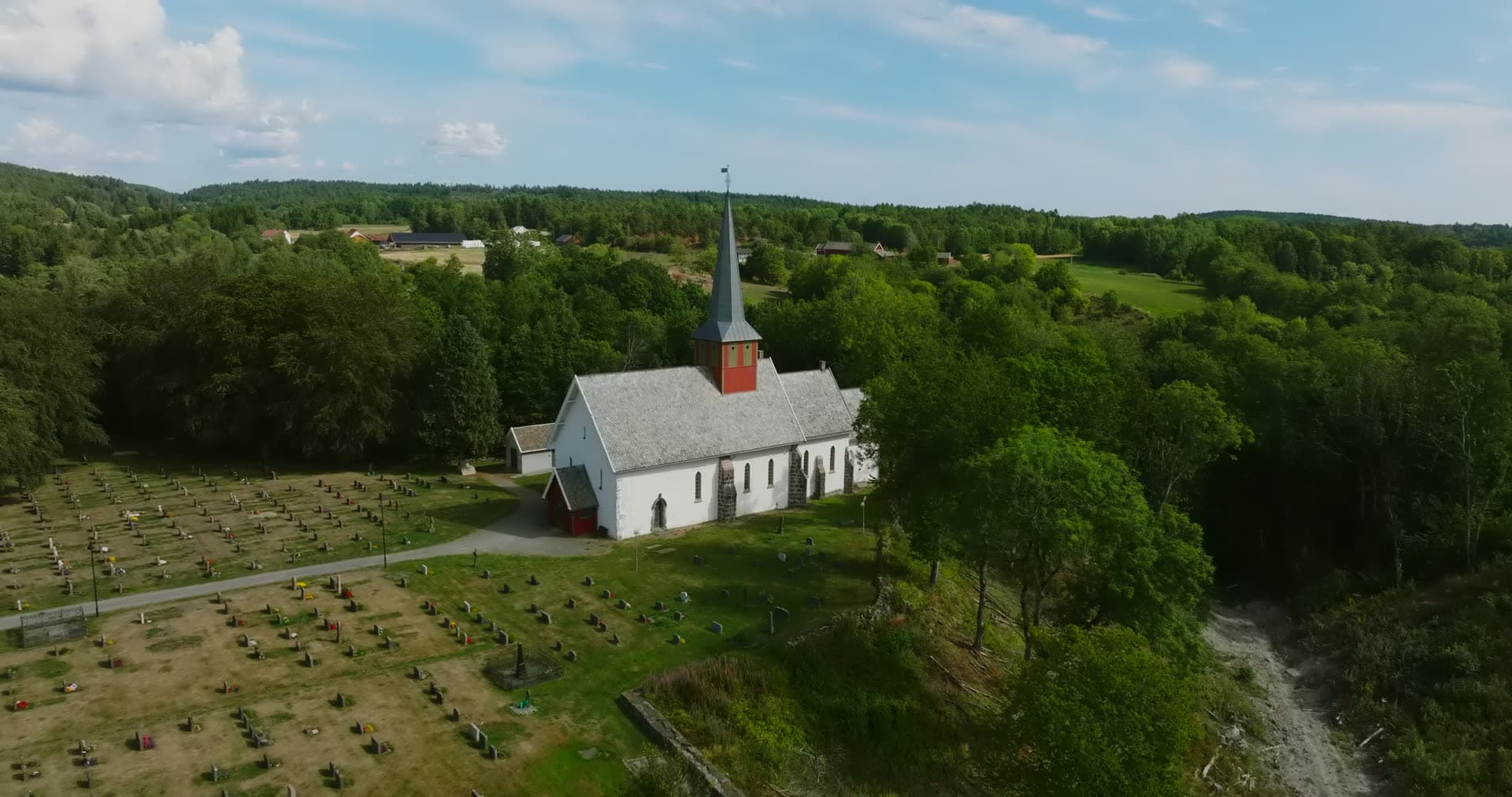 White church with red tower and graveyard, Rykene, Norway
