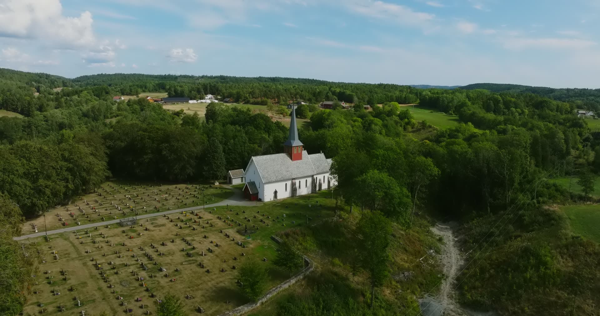 White church with spire beside graveyard, Rykene, Norway