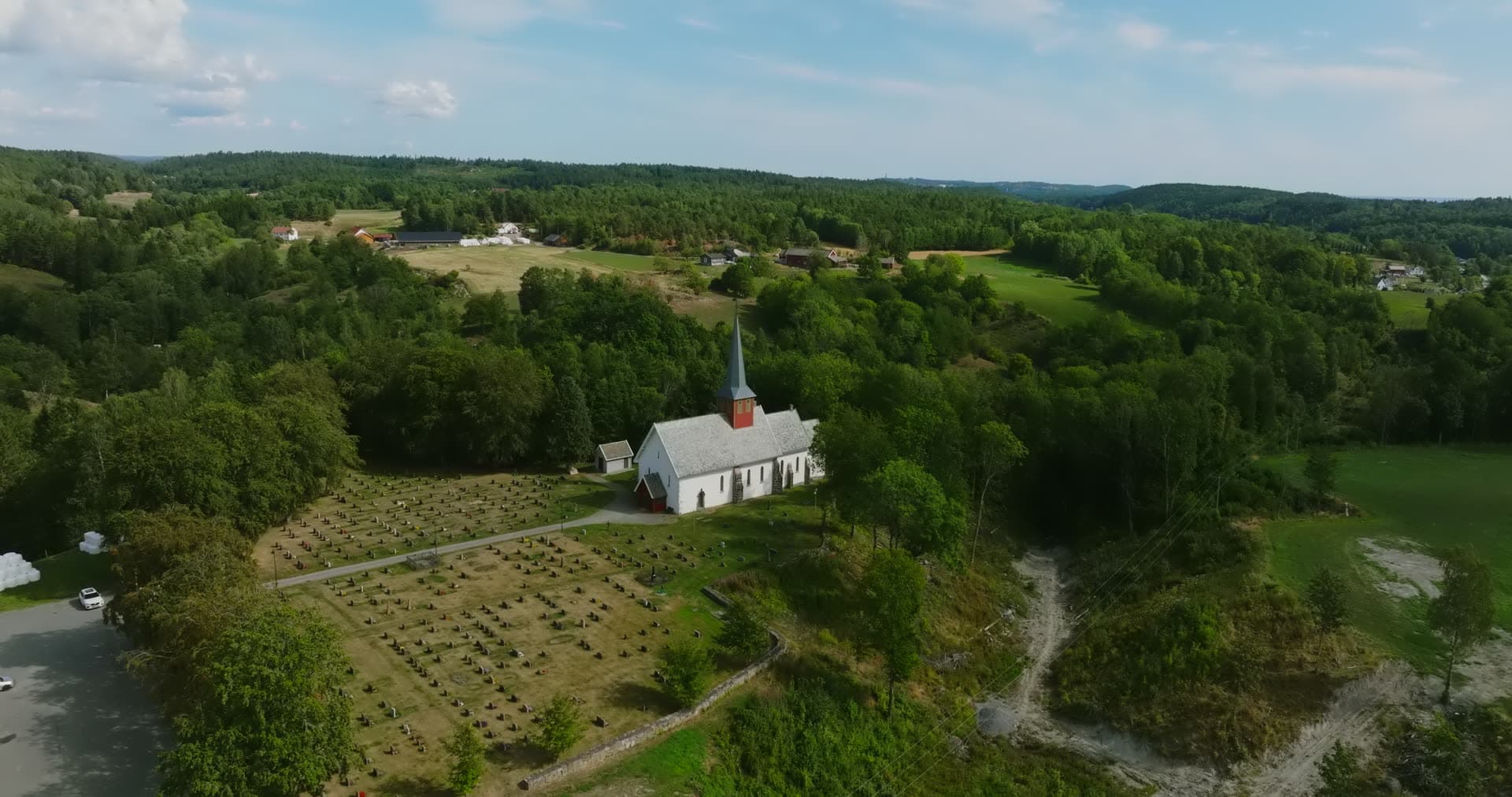Church spire above farmland, orbit closing in, Rykene, Norway