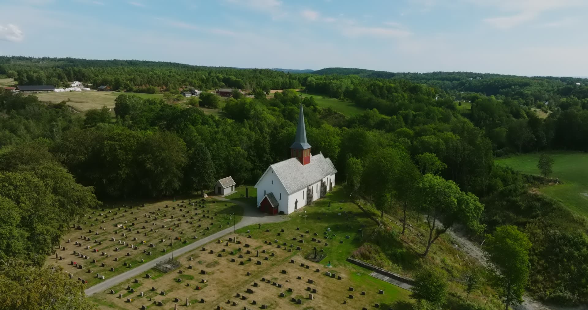 White wooden church and graveyard rows, Rykene, Norway