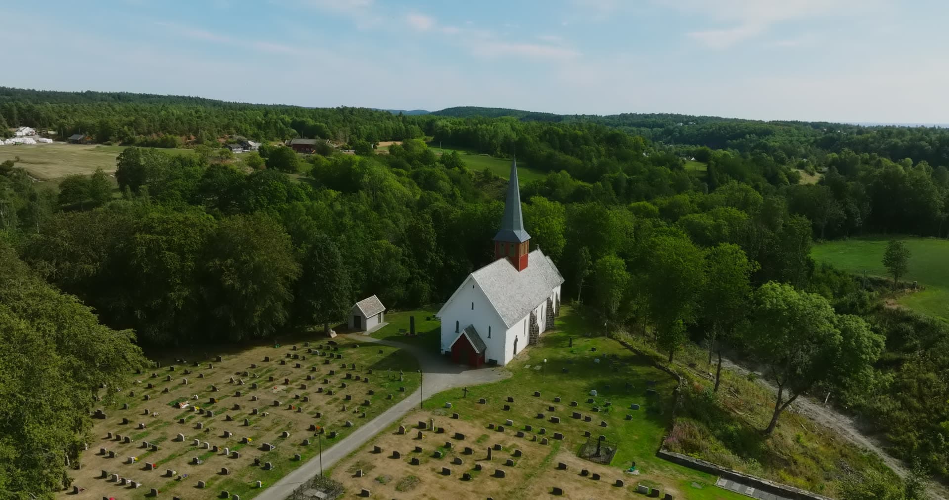 White wooden church and rows of graves, Rykene, Norway