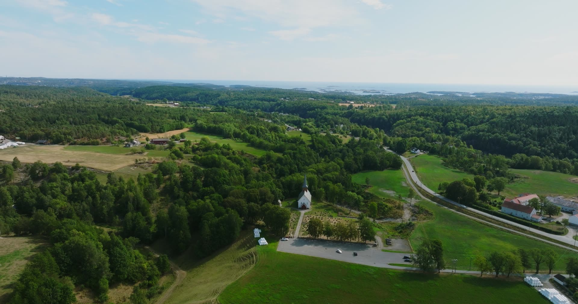White church and graveyard above farmland, Rykene, Norway