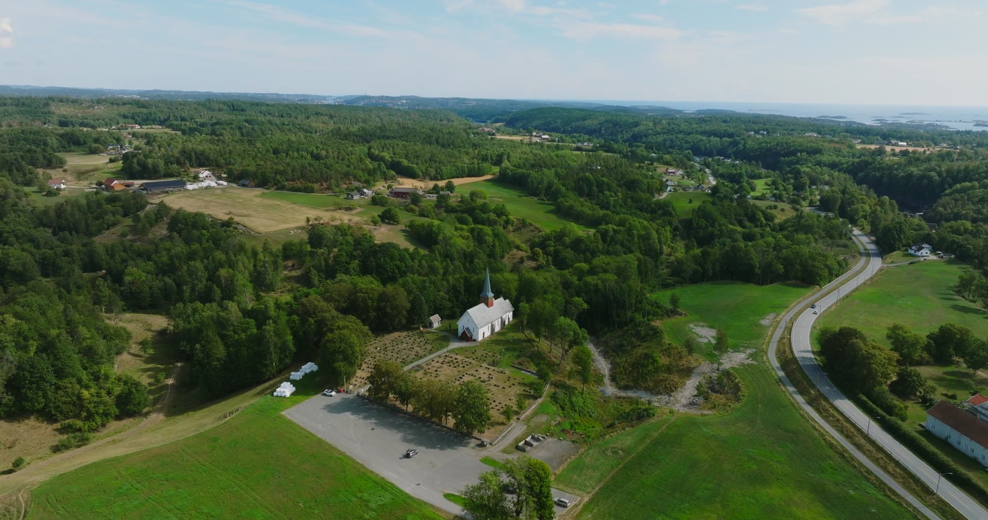 Hilltop chapel above farm fields and road, Rykene, Norway