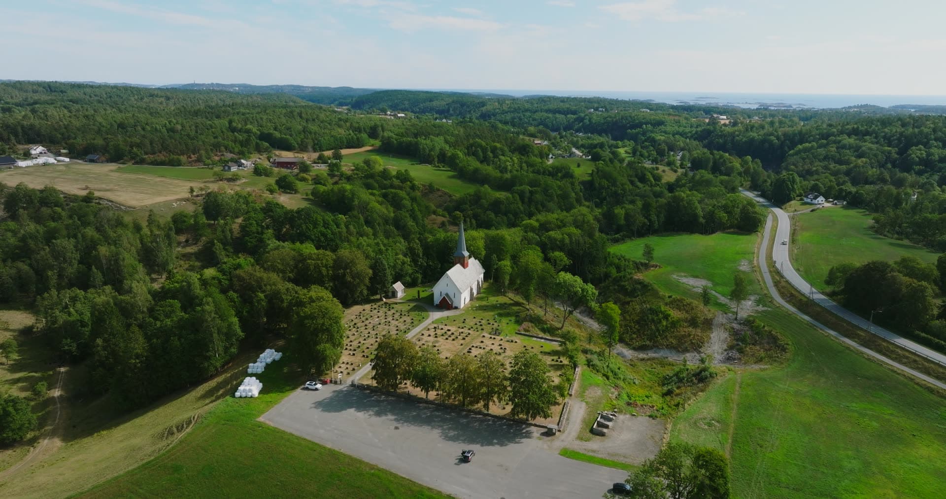 White church and graveyard beside highway, Rykene, Norway