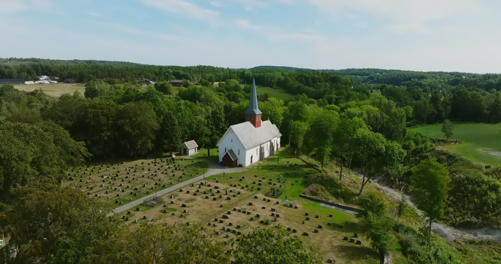 White church with spire above graveyard, Rykene, Norway