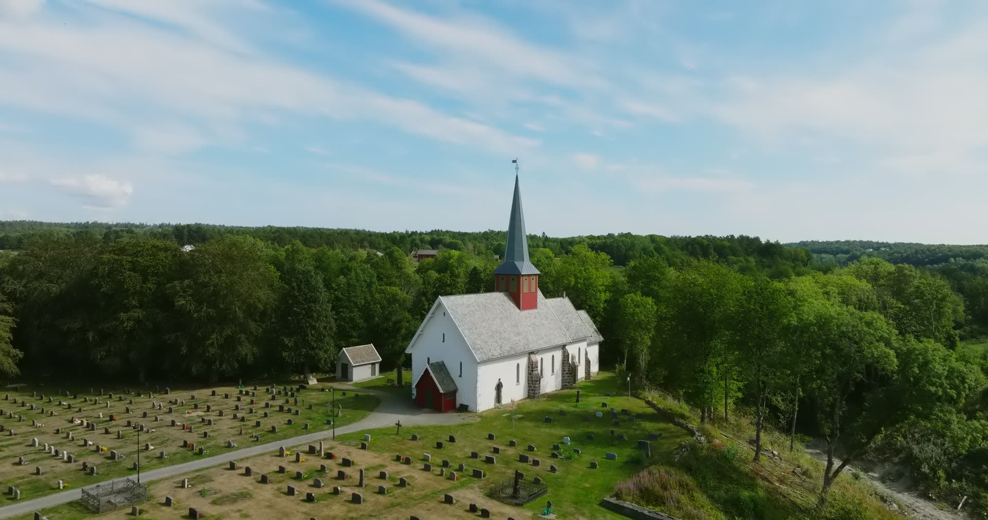 White stone church and hillside graveyard, Rykene, Norway