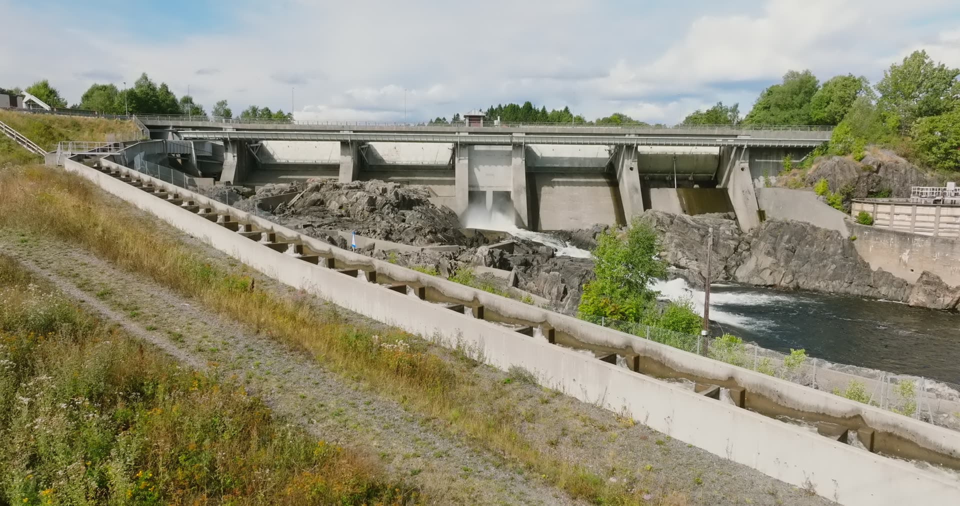 Concrete dam with spillway over rocky river, Rykene, Norway