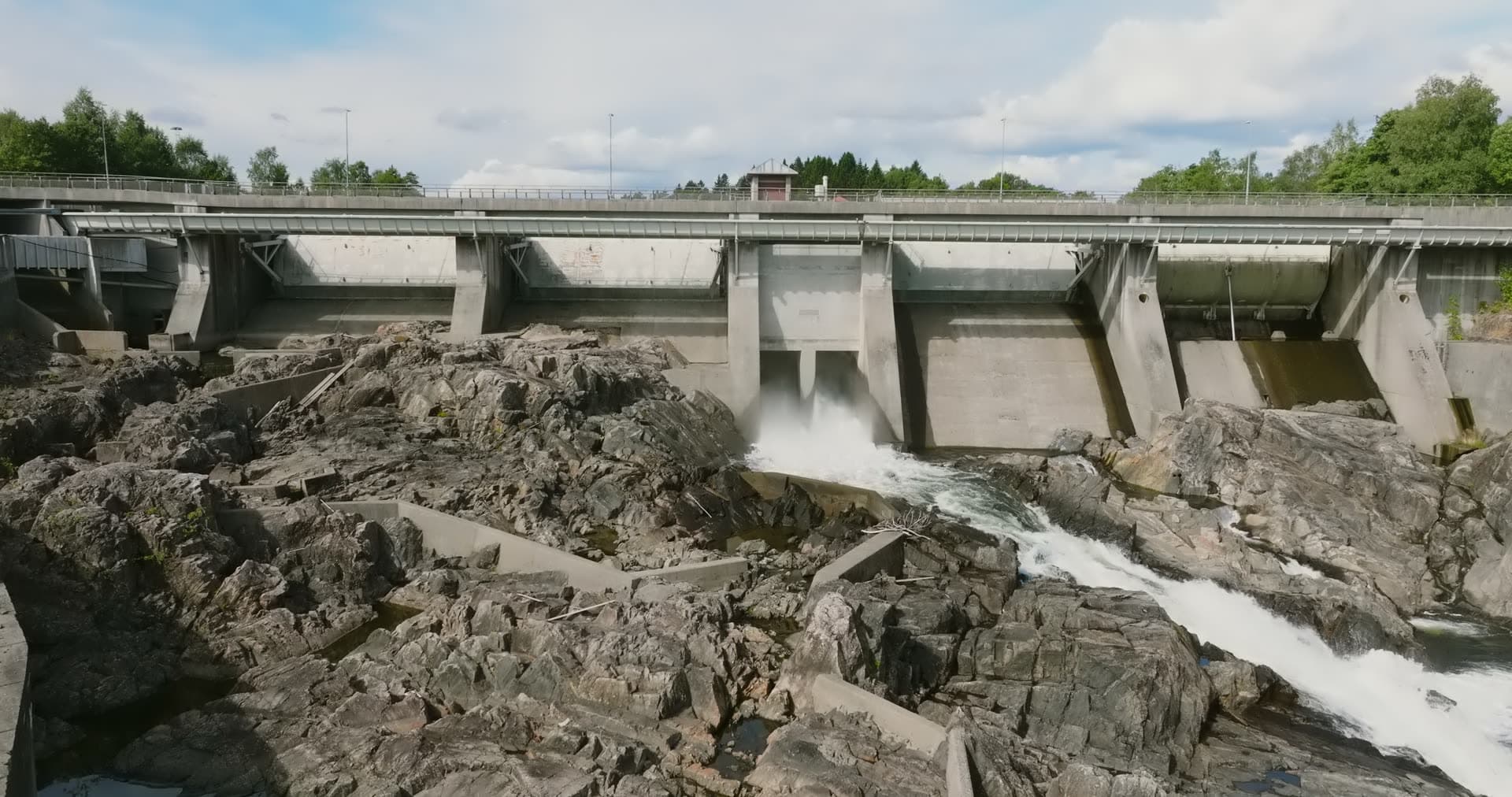 Concrete dam spilling water over bare rock, Rykene, Norway