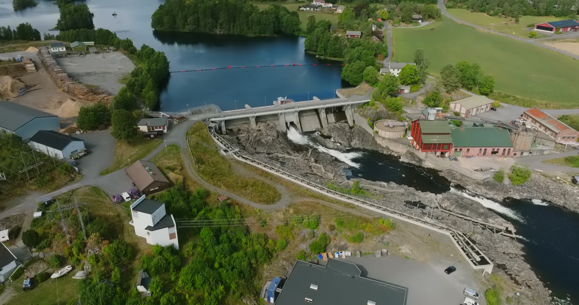 Dam spillway and rapids by red mill buildings, Rykene, Norway