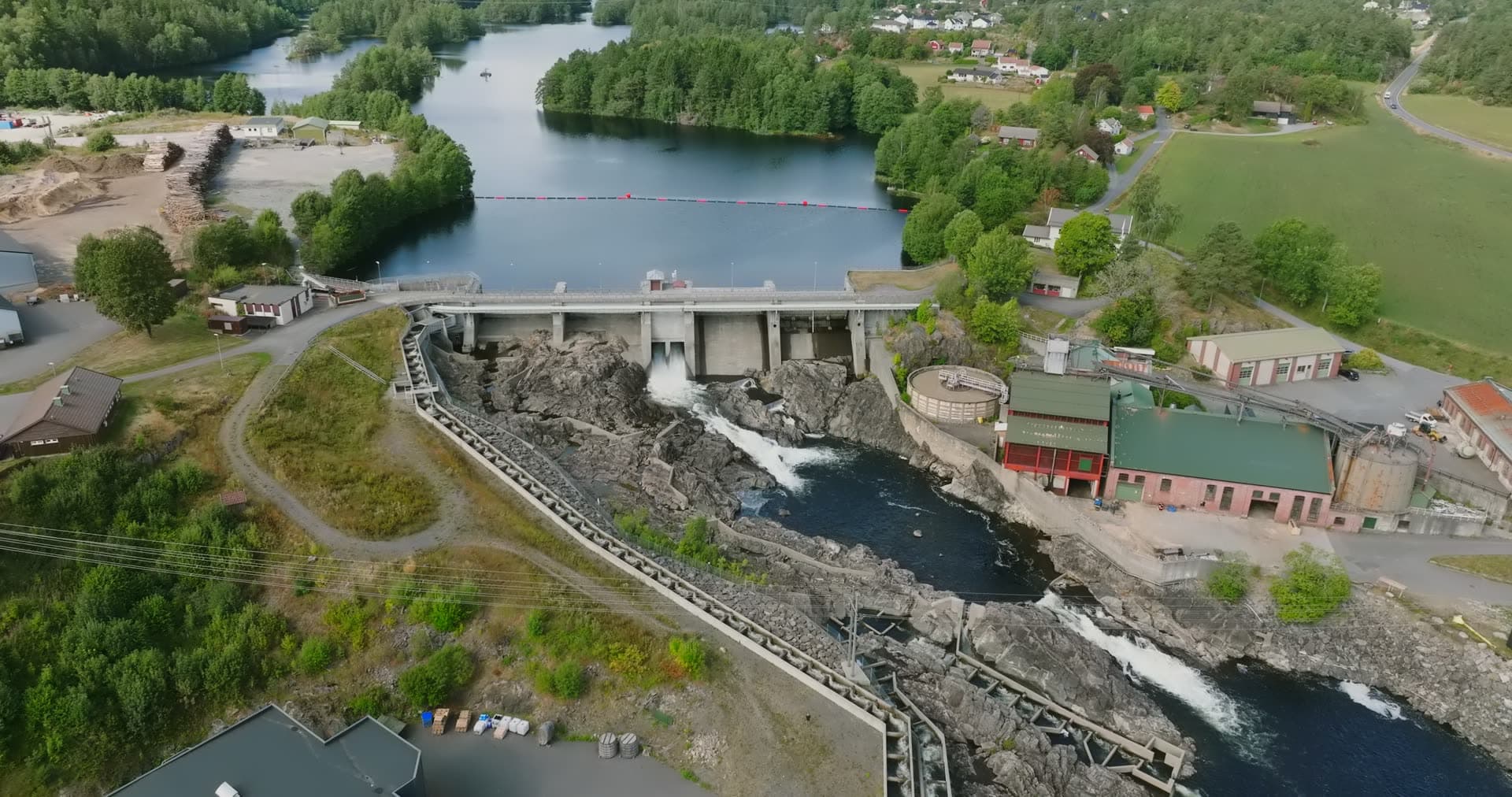 Concrete dam spilling water onto rocky river, Rykene, Norway