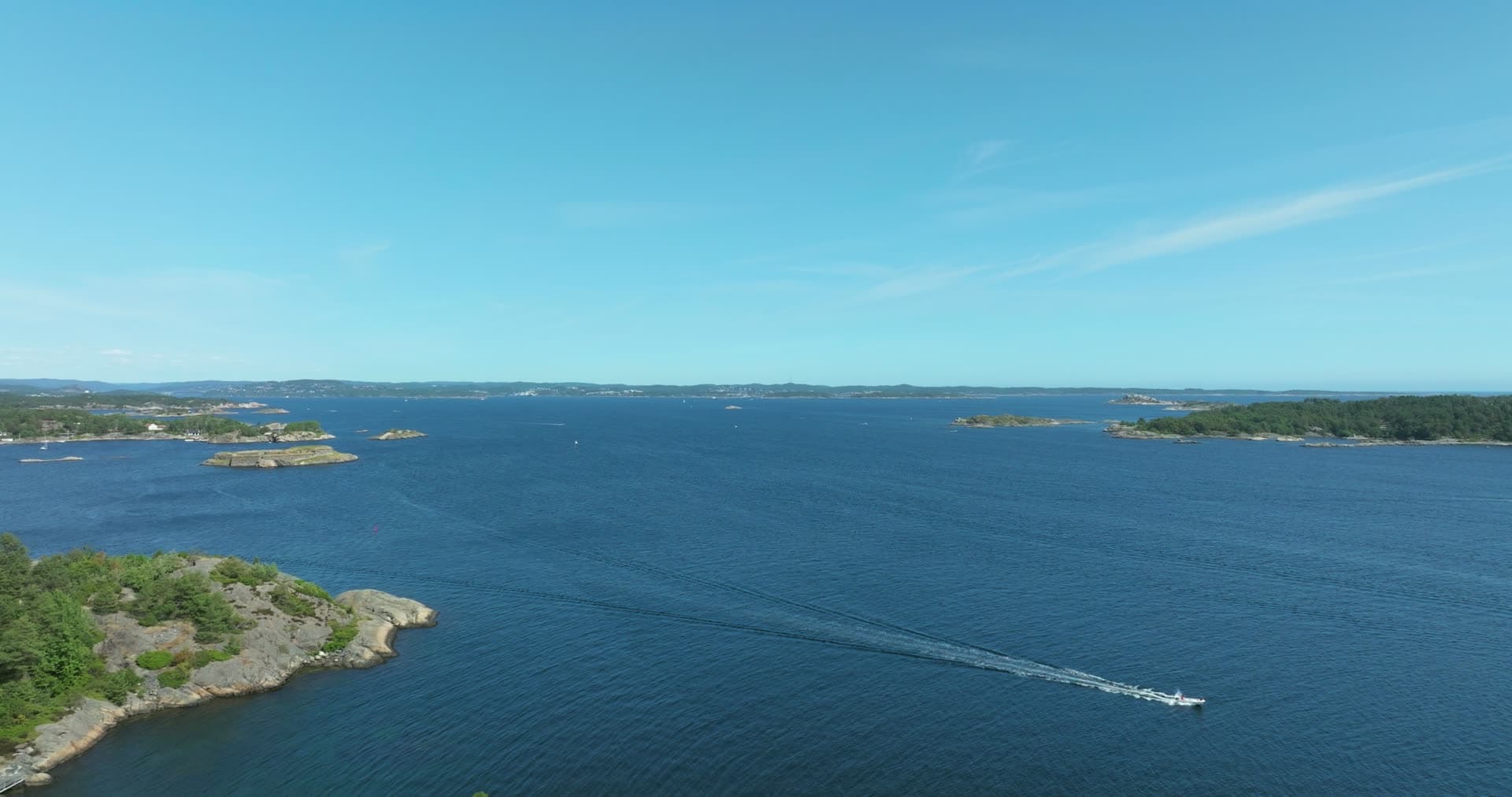 Motorboat wake crossing open archipelago, Skålevik, Norway