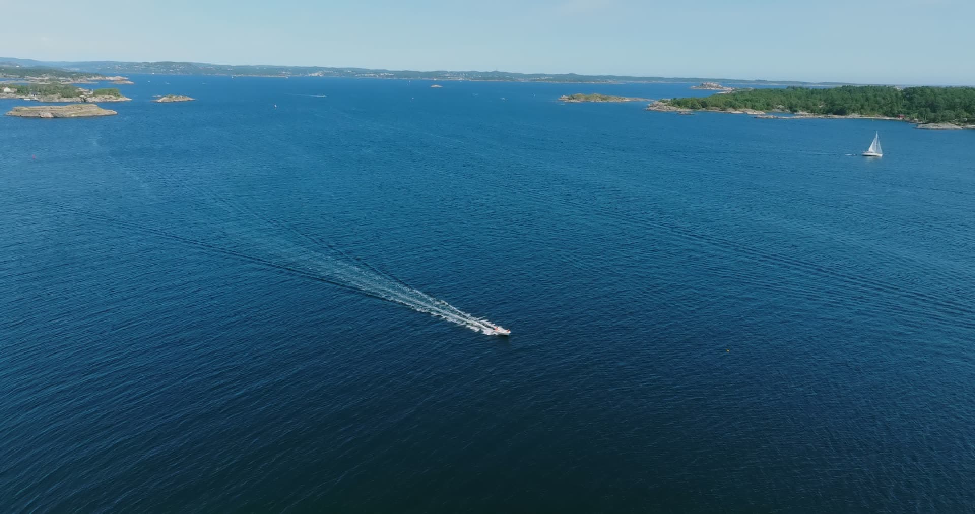 Speedboat trailing a long wake between skerries, Skålevik, Norway