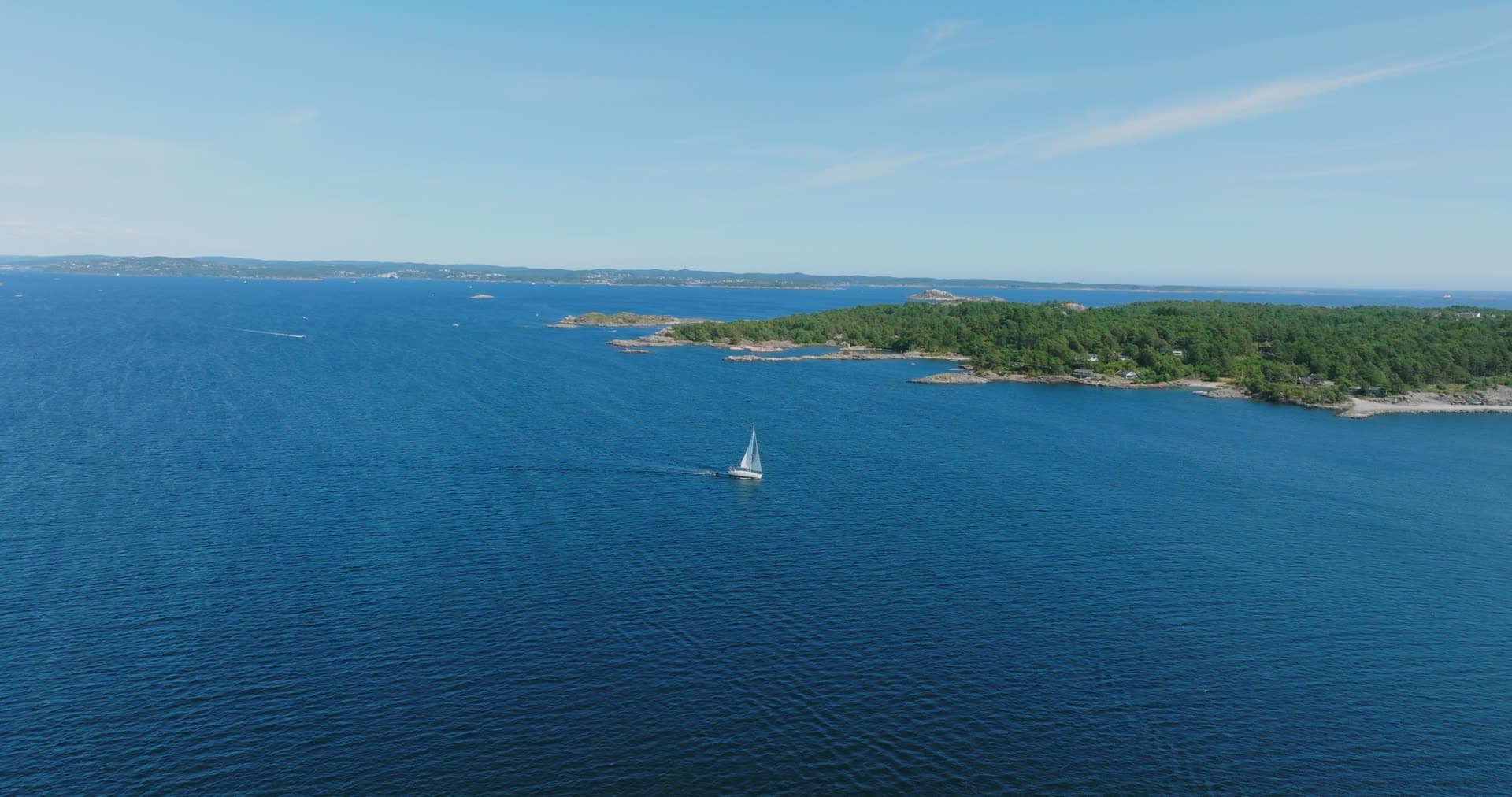 Sailboat under sail past a wooded islet, Skålevik, Norway