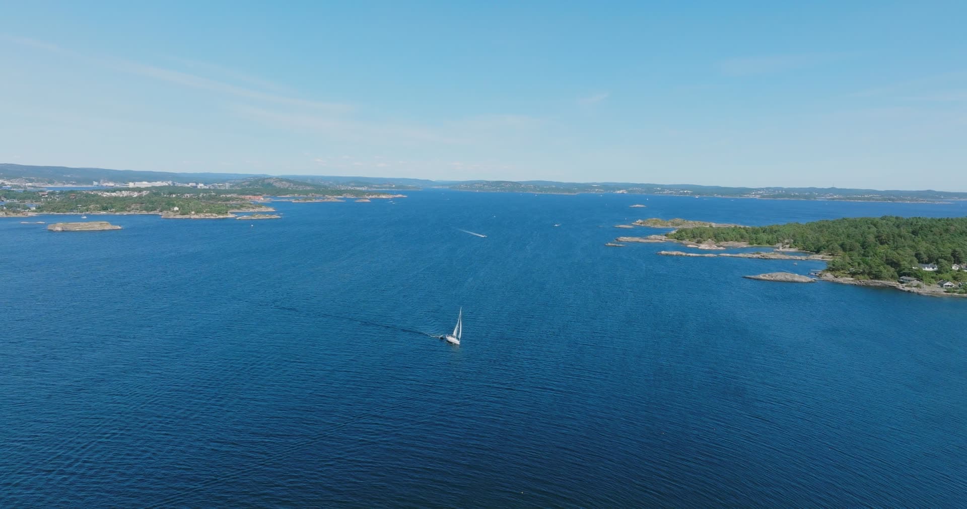Sailboat on open water below the city skyline, Skålevik, Norway