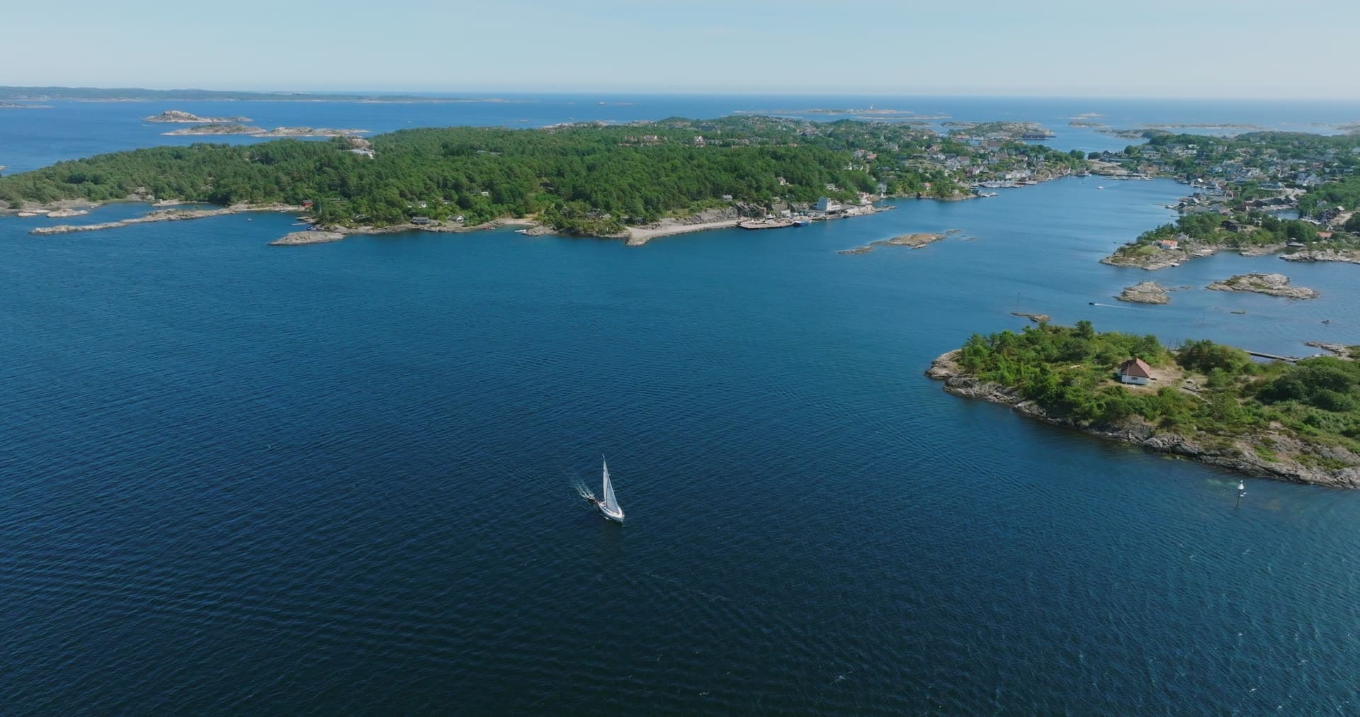 Lone cabin on an islet with the village beyond, Skålevik, Norway
