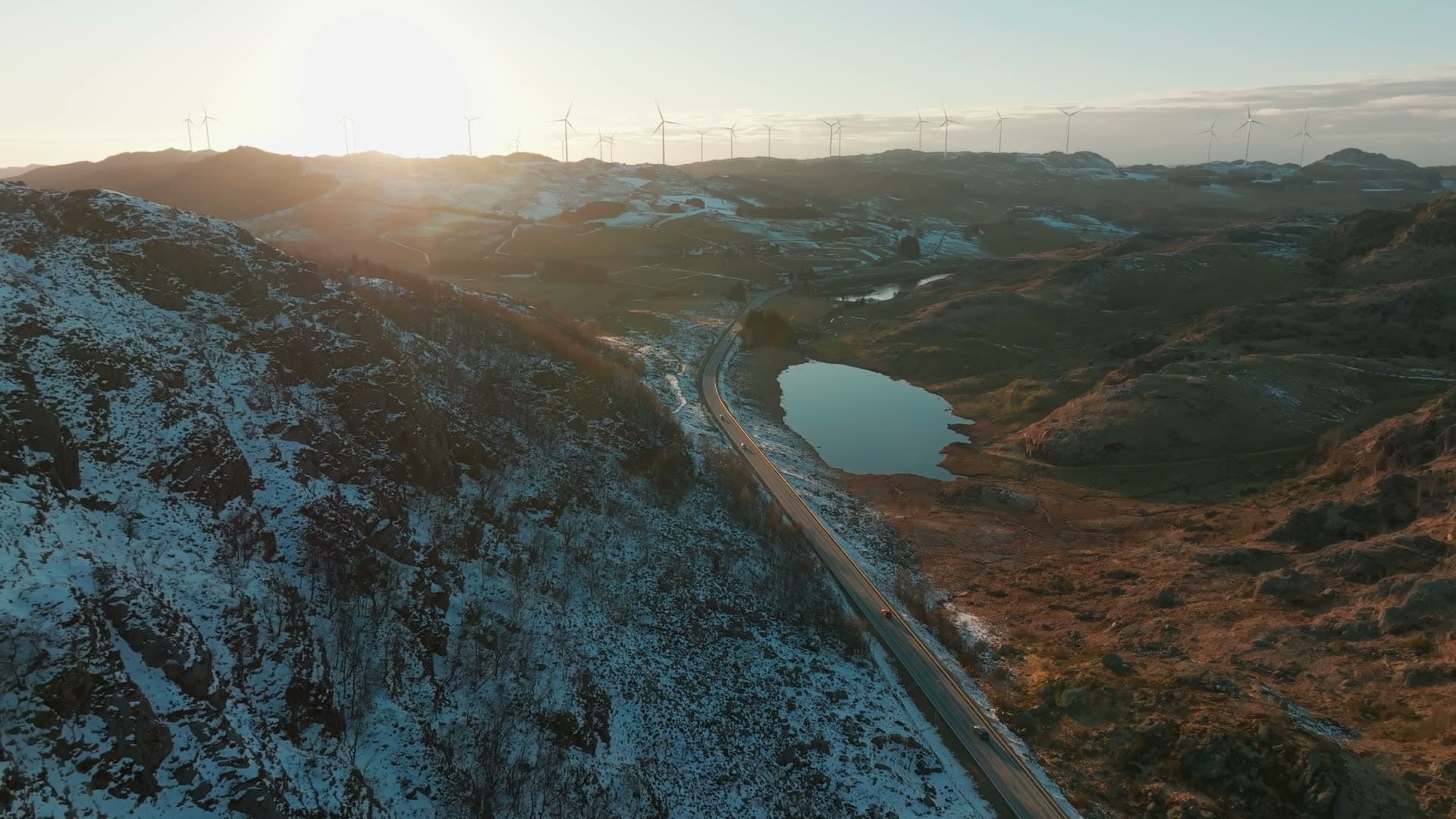Road past tarn below ridge wind turbines, Skurvenuten, Norway