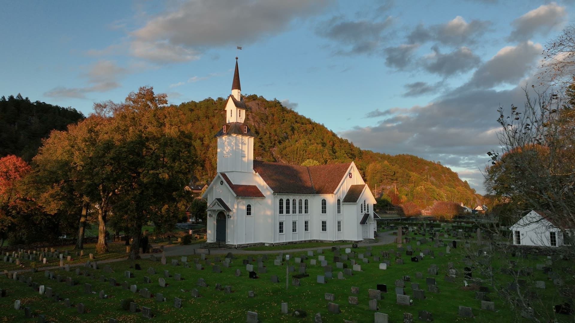 White wooden church and graveyard at sunset, Søgne, Norway