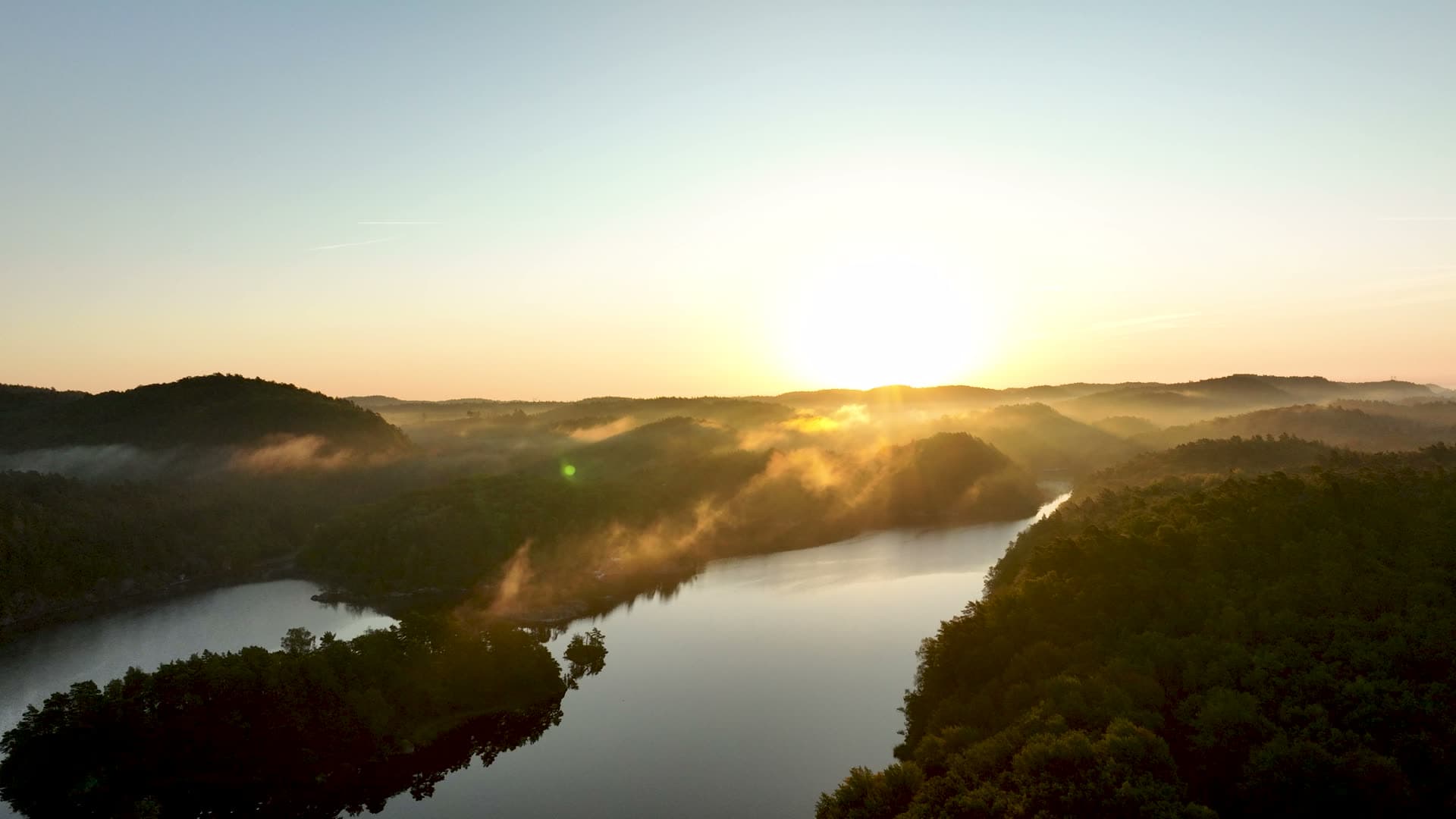 Mist drifting over forested lake at sunrise, Søm, Norway
