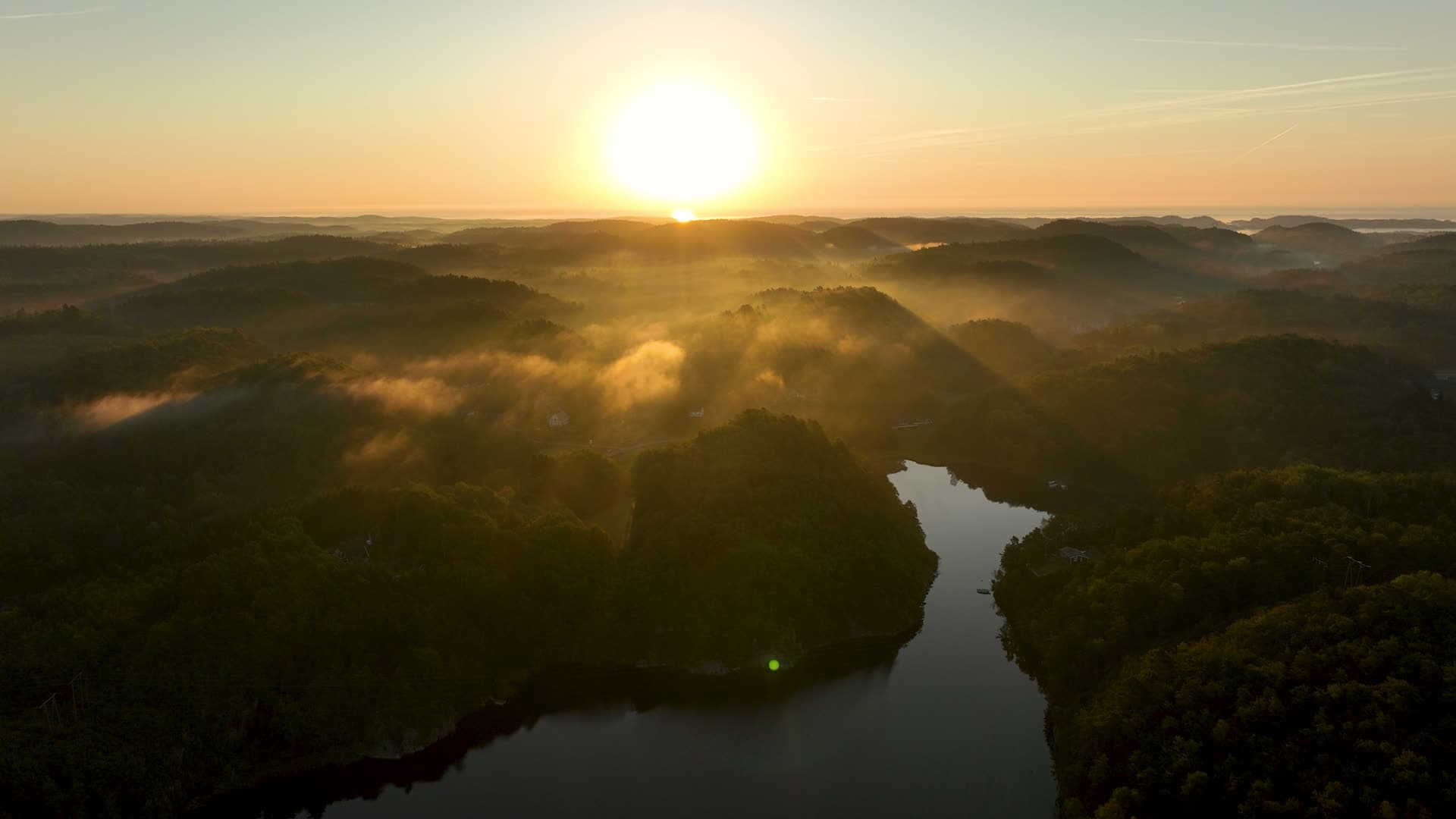Mist over forested hills and narrow lake, Søm, Norway