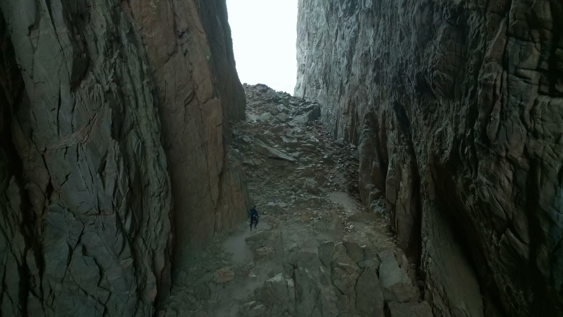 Lone hiker on scree inside rock tunnel, Torghatten, Norway