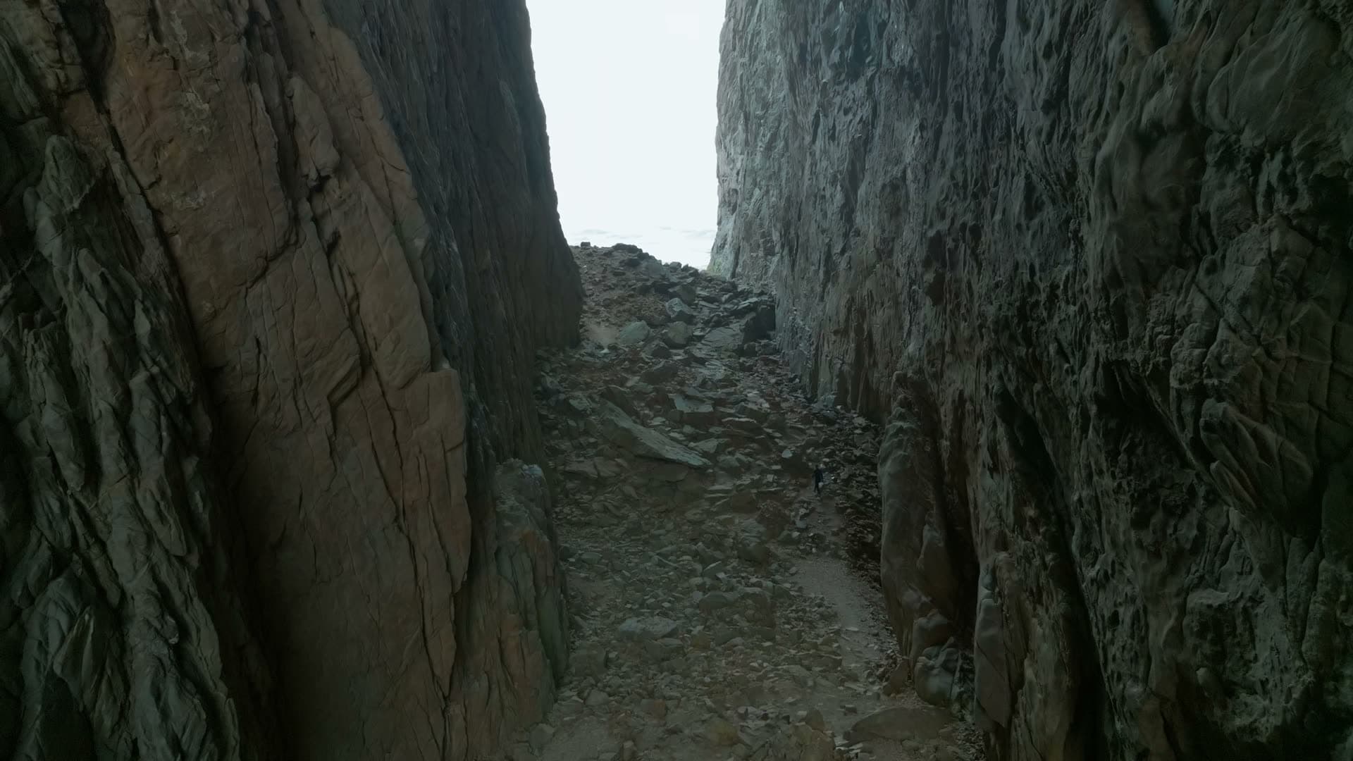 Hiker in narrow rock tunnel with scree, Torghatten, Norway