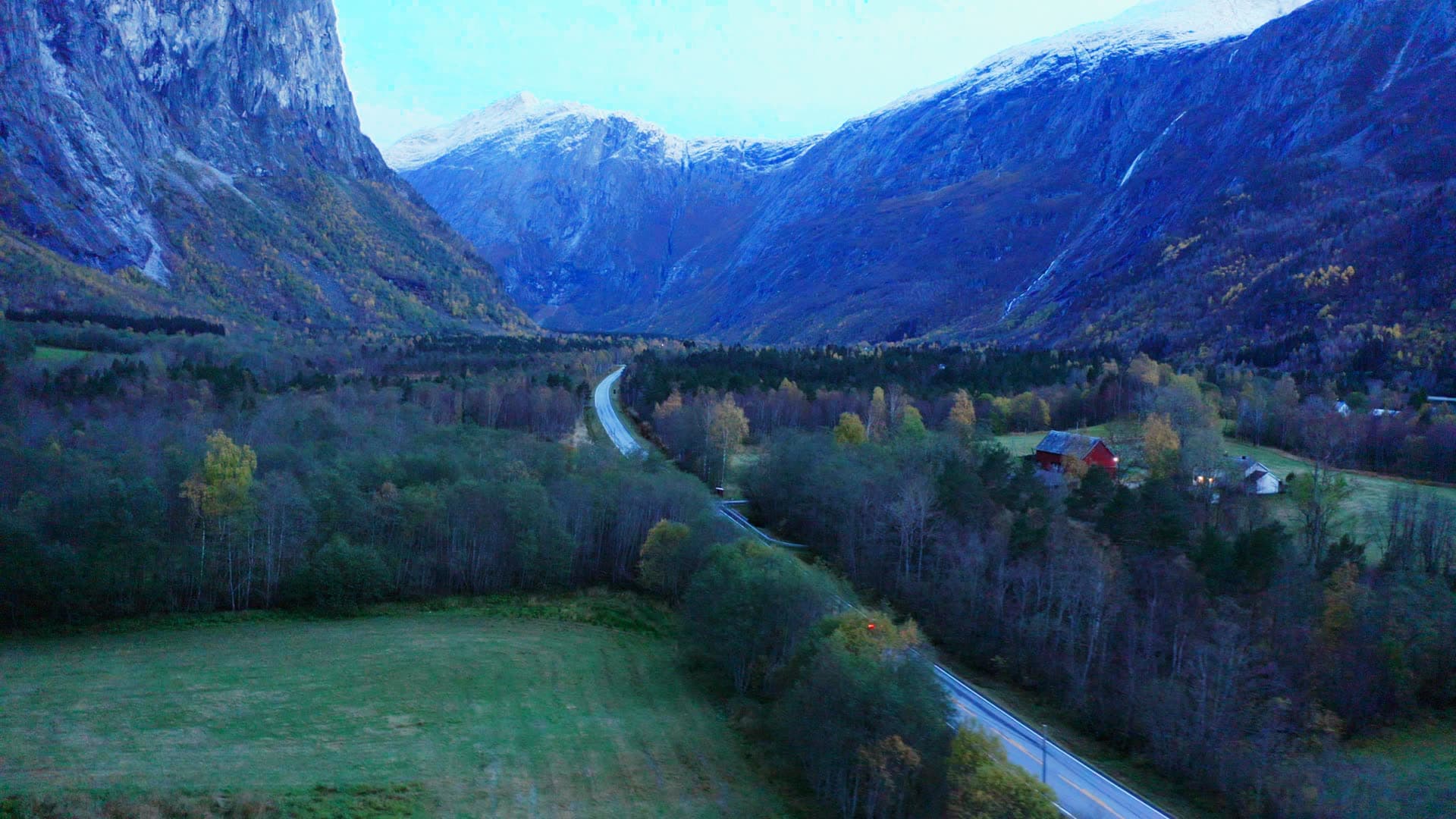 Red car on valley road past red barn, Trollstigen, Norway