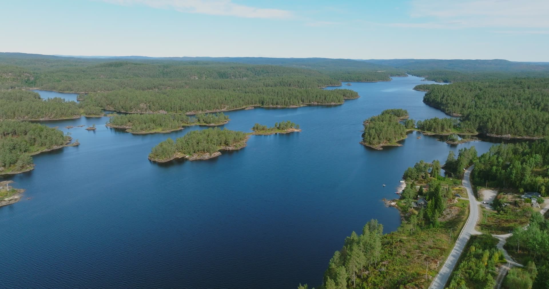 Road along lake with pine-covered islets, Vassbotn, Norway