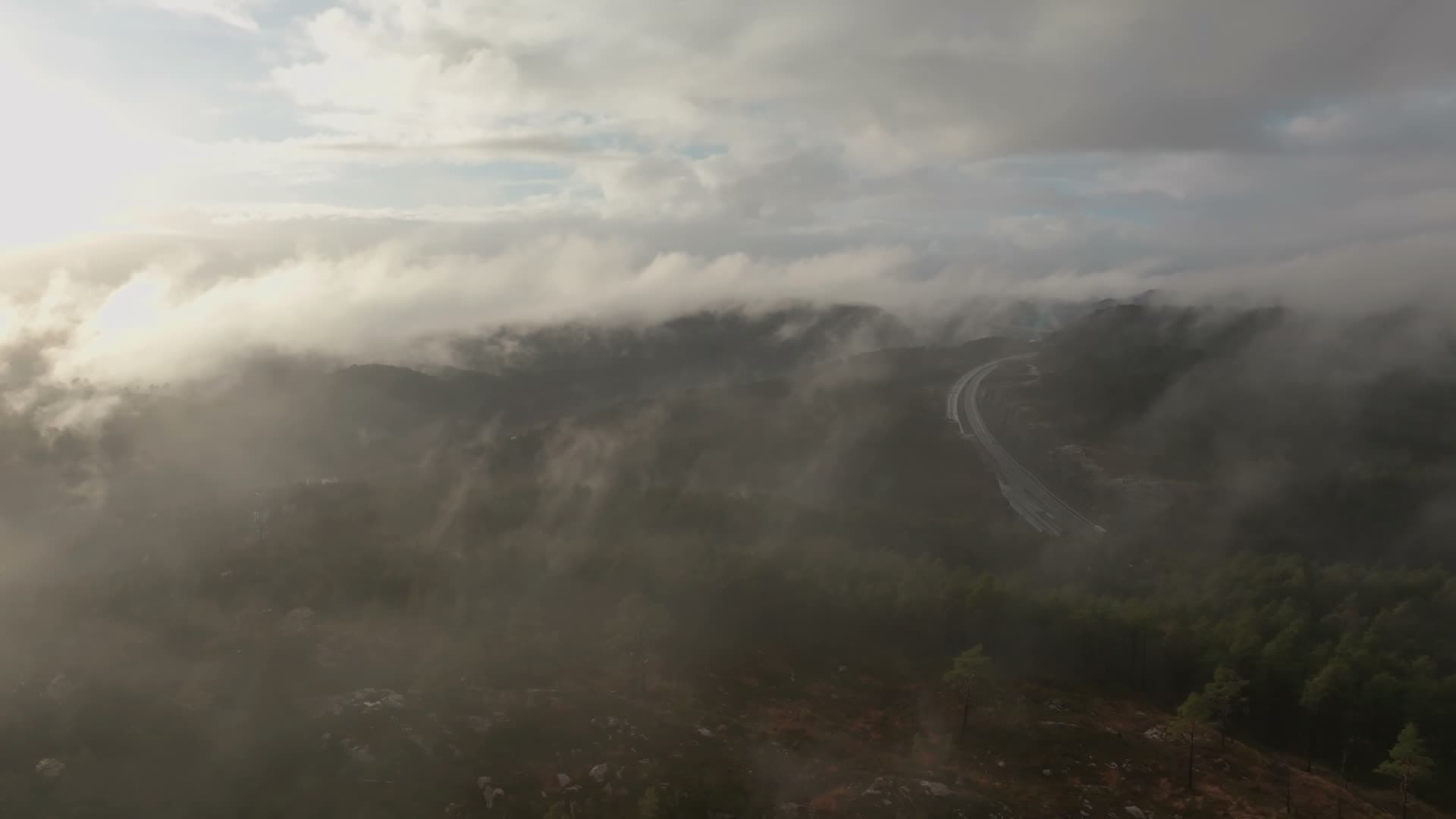 Low cloud over forested ridge and highway, Vedderheia, Norway