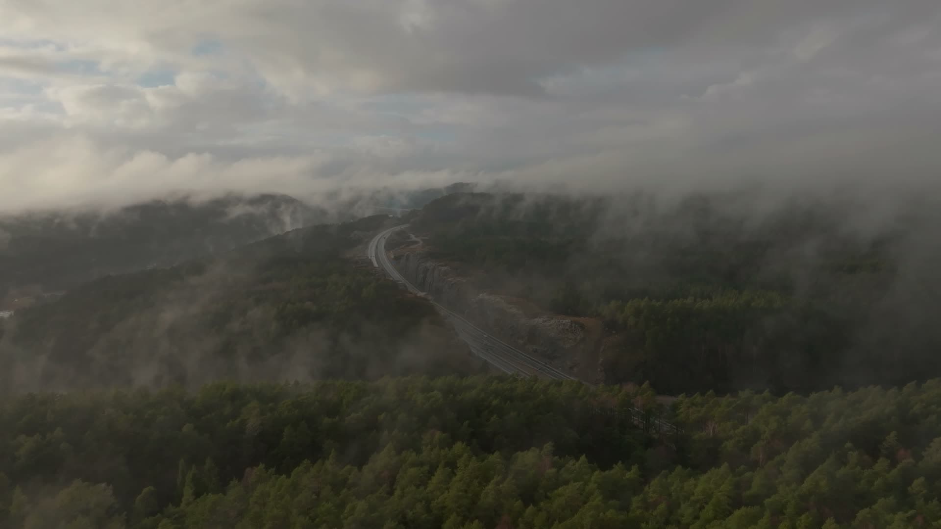 Low cloud over highway cut through forest, Vedderheia, Norway