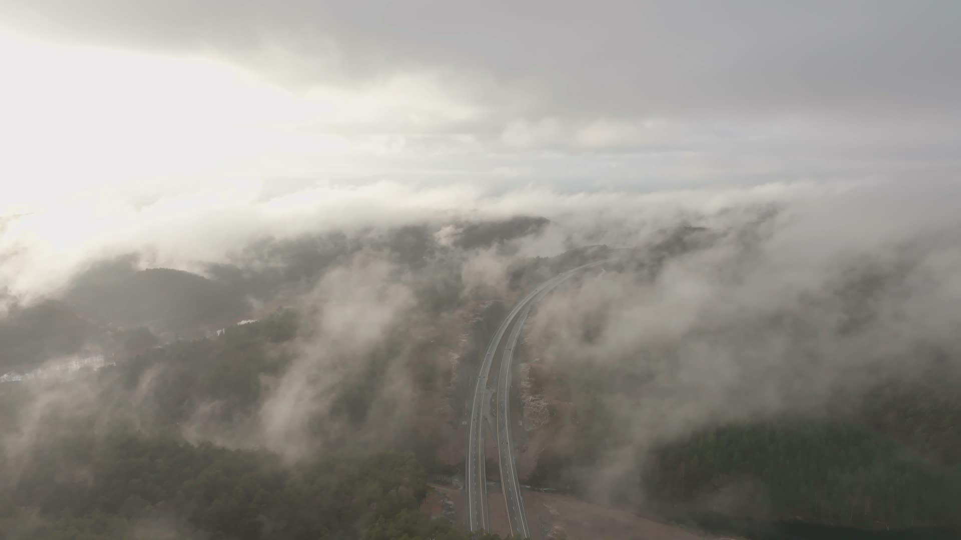 Low cloud drifting over forest highway, Vedderheia, Norway