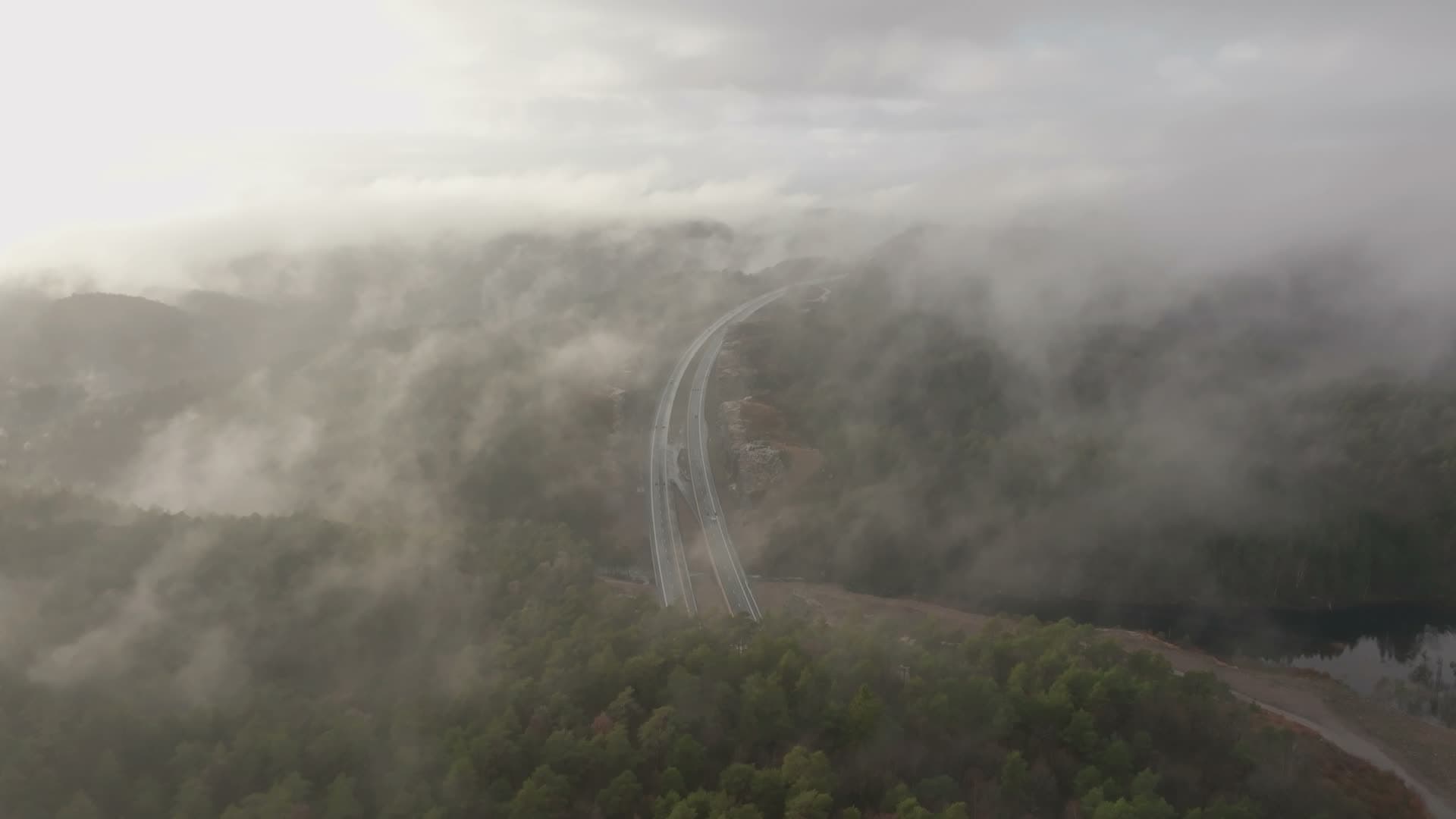 Low clouds over highway through forest, Vedderheia, Norway