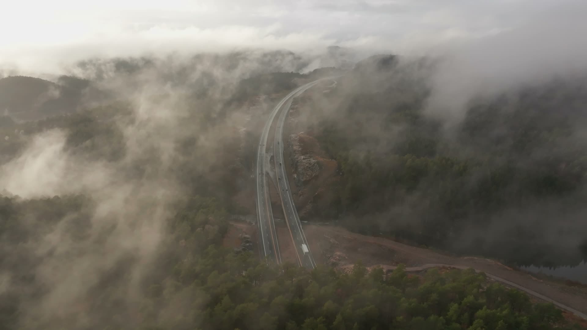 Low clouds over motorway cut in forest, Vedderheia, Norway