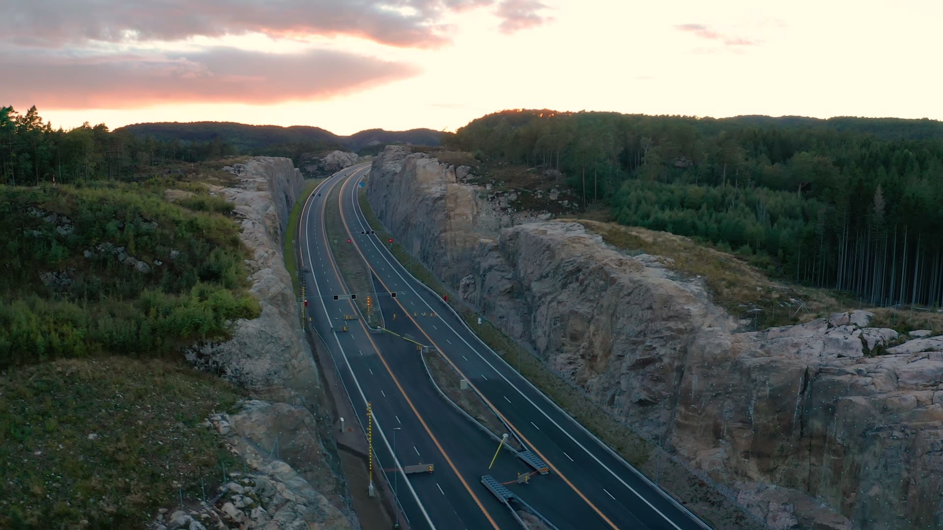 Highway through blasted rock cut at sunset, Vedderheia, Norway