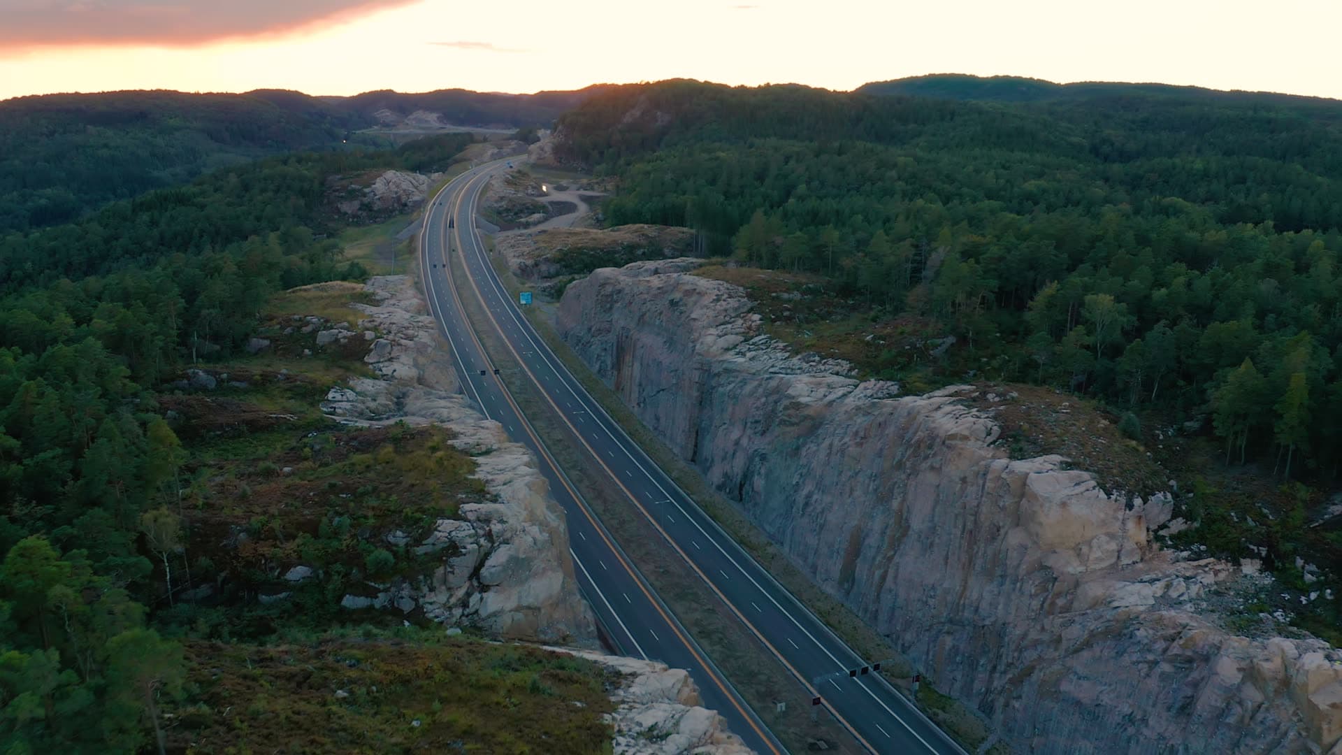 Highway through blasted rock cut at dusk, Vedderheia, Norway