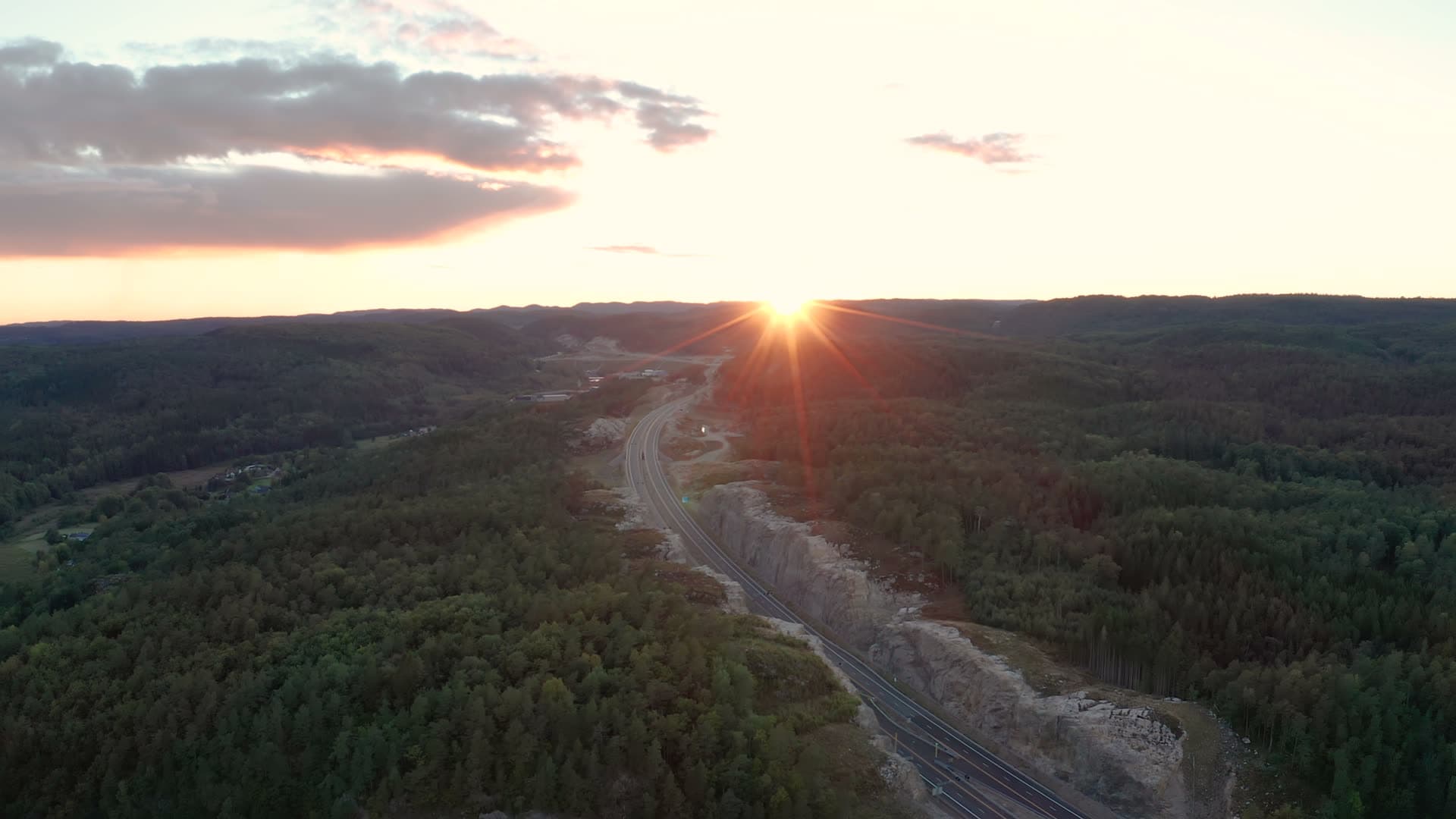 Highway cut through rock and forest at sunset, Vedderheia, Norway