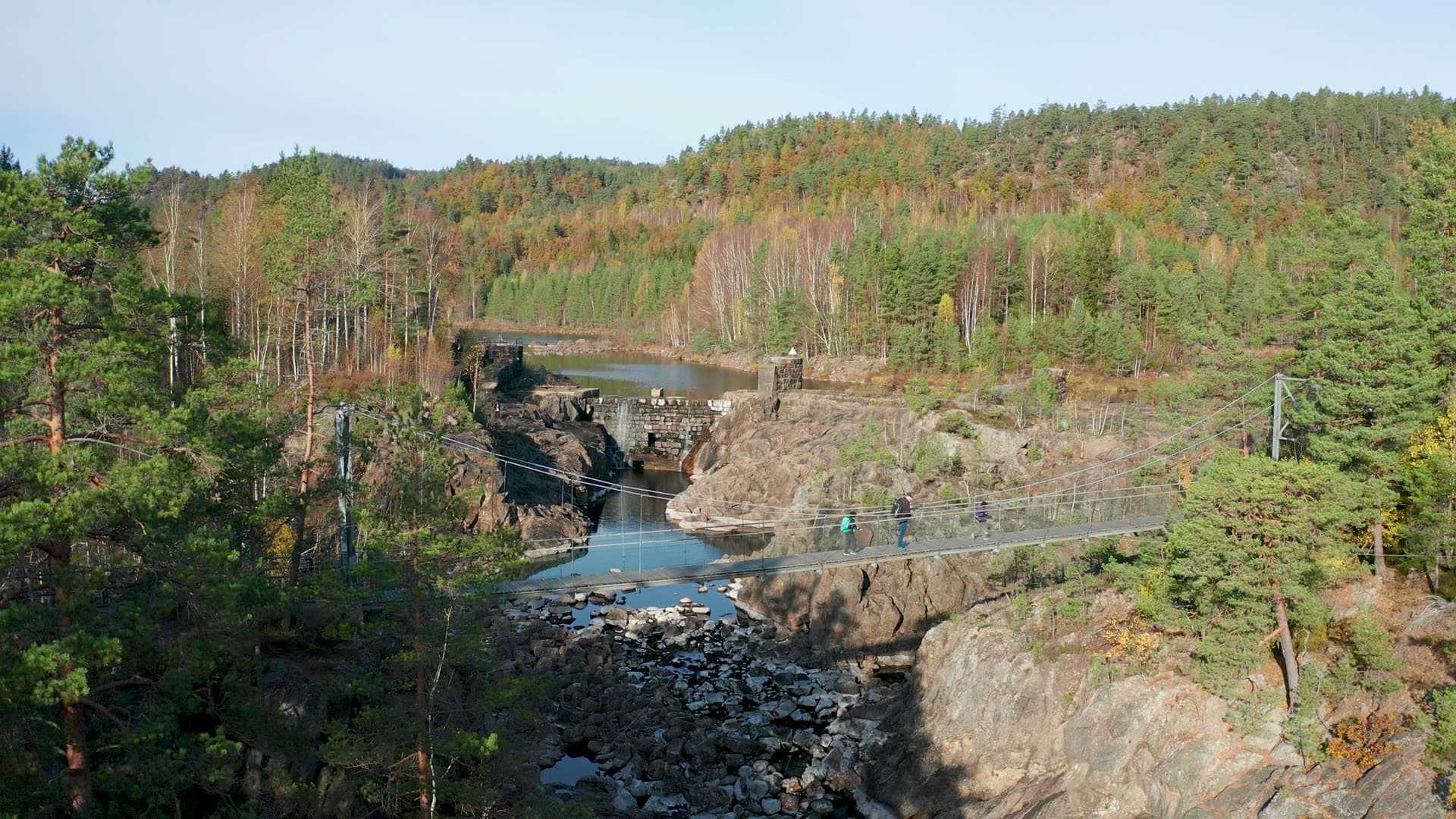Hikers on suspension bridge below dam, Vennesla, Norway