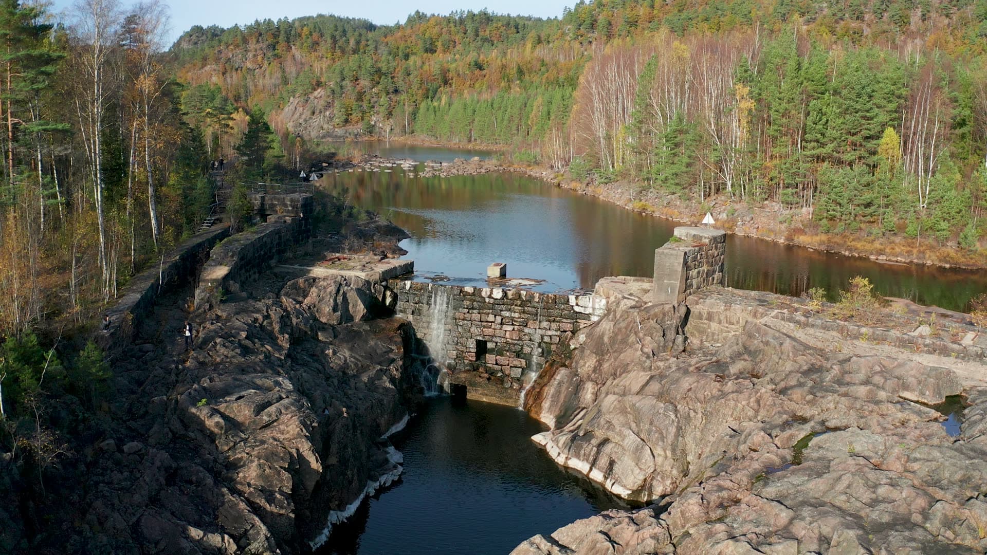 Old stone dam leaking into rock gorge, Vennesla, Norway