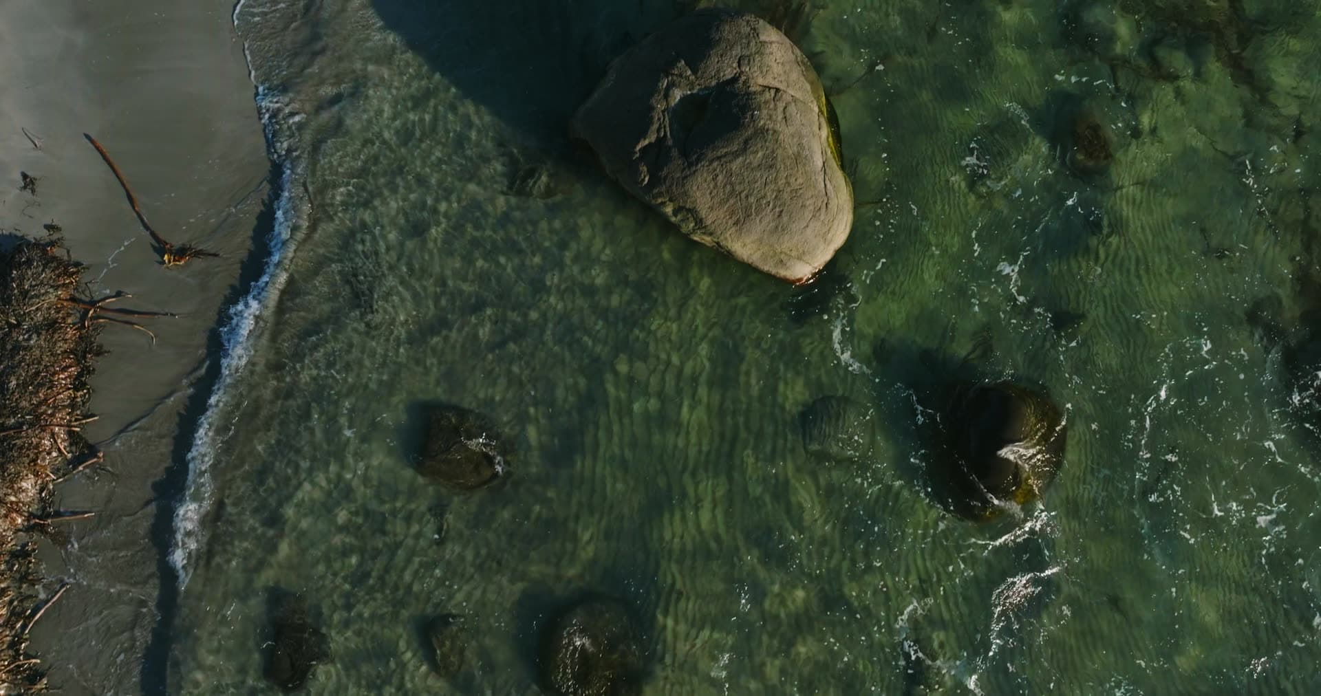 Boulder in clear shallows at sandy shoreline, Vestbygd, Norway