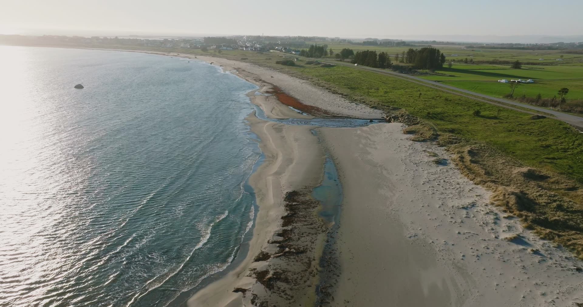 Sandy beach with tidal pools by farmland, Vestbygd, Norway