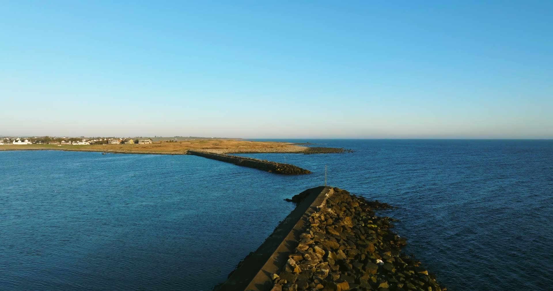 Two rock breakwaters off a flat shore, Vestbygd, Norway