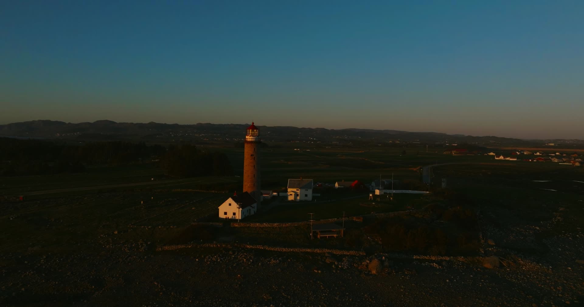 Lighthouse and white keeper houses at dusk, Vestbygd, Norway
